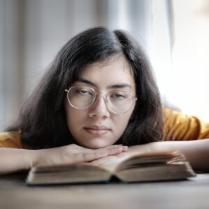 tired female student lying on book in library