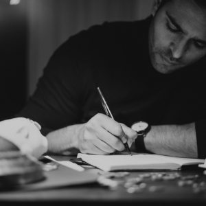 crop man taking notes in copybook in dark home office