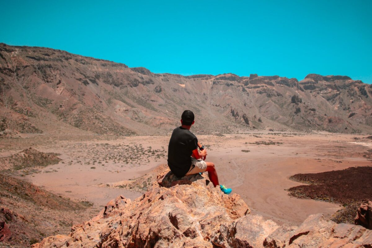 man sitting on brown rocky mountains
