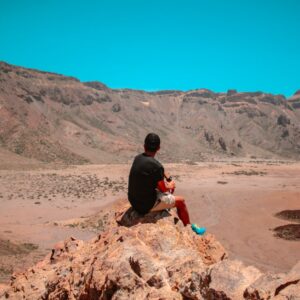 man sitting on brown rocky mountains