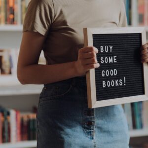 man in brown crew neck t shirt and blue denim jeans holding black and white book
