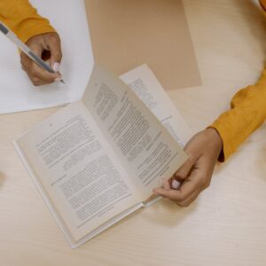 person in yellow long sleeve shirt holding white pen writing on white paper