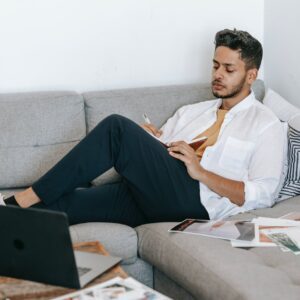 man taking notes in notebook near laptop