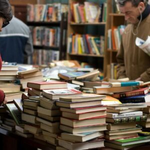 woman and man standing beside piles of books