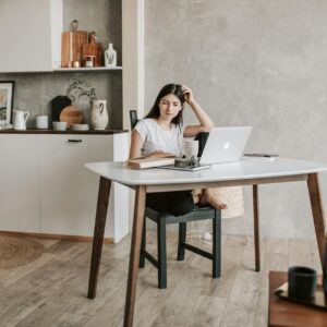 focused young woman with laptop and books at home
