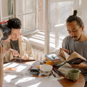 Group of college students collaborating and studying together on a sunny day in a dorm room.