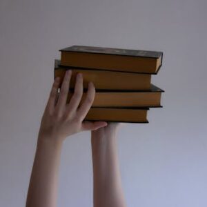 Several books held by hands against a plain backdrop, perfect for educational themes.