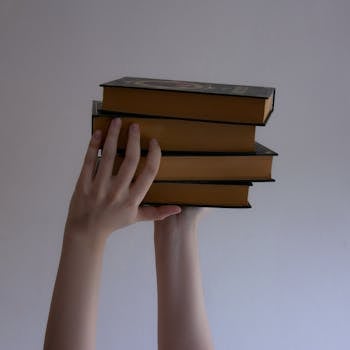 Several books held by hands against a plain backdrop, perfect for educational themes.